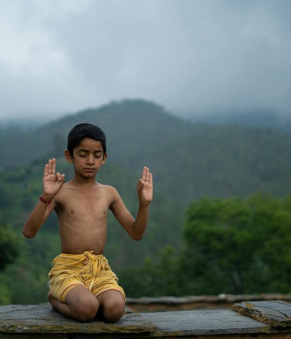 Person meditating outdoors with a beautiful natural landscape behind them.